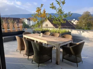Gesamtansicht einer bepflanzten Dachterrasse mit Holz-Esstisch