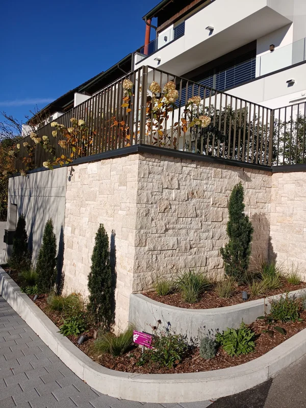 Natursteinverblendung mit Bepflanzung entlang einer Mauer